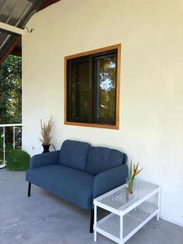 a blue couch in a living room with a window at Big hug home-Forest House in Ban Takhrai