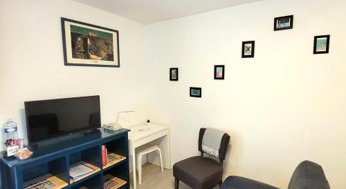 ein Wohnzimmer mit einem TV und einem Schreibtisch mit einem Stuhl in der Unterkunft Les Gîtes d'Angres - gîte n°2 in Angres