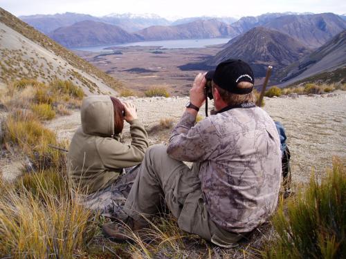 two people sitting on a hill taking pictures of a mountain at Abisko Lodge in Methven