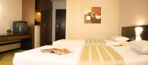a hotel room with two beds and a television at Rothman Hotel in Manila