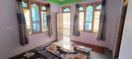 a bedroom with windows and a bed in a room at OTW Guest House & Mountain Cafe in Kasol