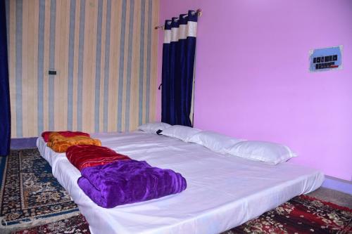 a large white bed with colorful sheets and pillows at S & H Stay Home in Mysore