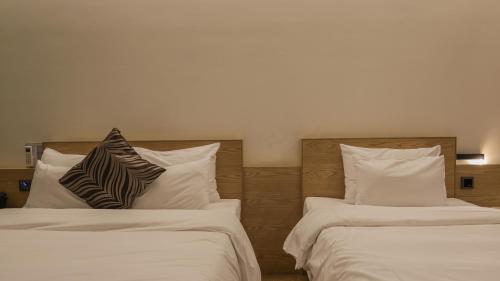 two beds with pillows sitting next to each other at Pangyo Business & Tourist Hotel KYND in Seongnam