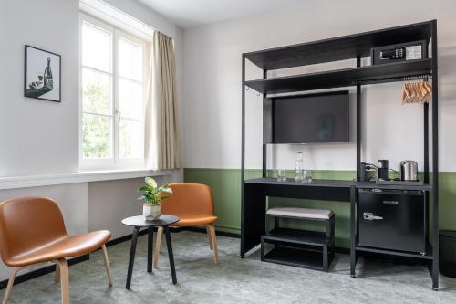 um quarto com uma secretária, cadeiras e uma televisão em Hotel Goldener Stern - contactless check-in em Lucerna