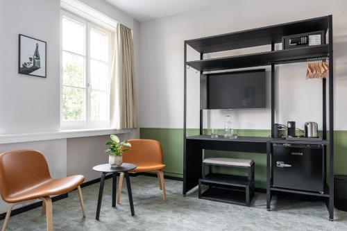 a room with a desk and chairs and a television at Hotel Goldener Stern - contactless check-in in Lucerne