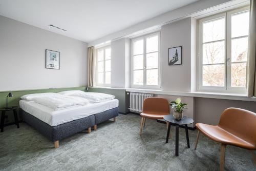 a bedroom with a bed and two chairs and windows at Hotel Goldener Stern - contactless check-in in Luzern