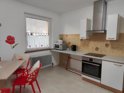 a kitchen with white cabinets and a table and a red chair at Pension Hexagon in Spittal an der Drau