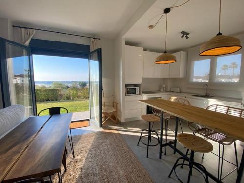 een keuken en een woonkamer met een houten tafel en stoelen bij Bajo con vistas increíbles in El Rompido