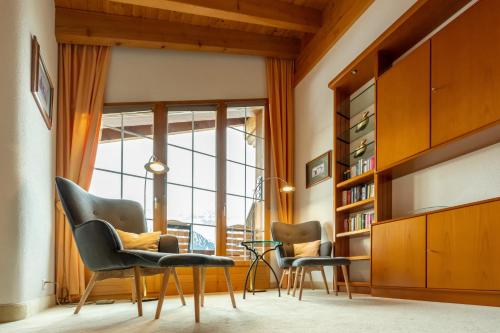 a living room with two chairs and a book shelf at Hotel Bellwald in Bellwald