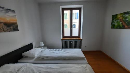 a white bedroom with a bed and a window at Black Stone Apartments - Lörrach in Lörrach