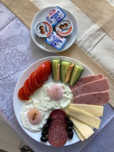 a plate of breakfast food with eggs sausage and cheese at Hotel Rudo in Predeal