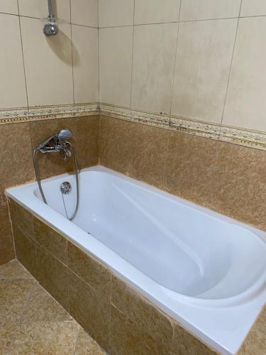 a white bath tub in a tiled bathroom at Jovian guest house in Dubai