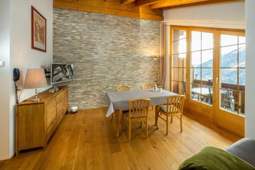 a dining room with a table and chairs and a brick wall at Hotel Bellwald in Bellwald