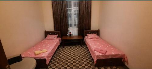 two beds in a room with a window at Гостевой дом Мусо in Tashkent