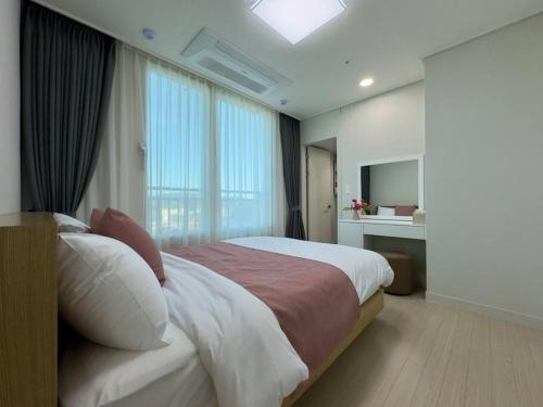 una camera da letto con un grande letto con una grande finestra di Eunhasu D&M Residence Cheongcho 3 a Daejeon