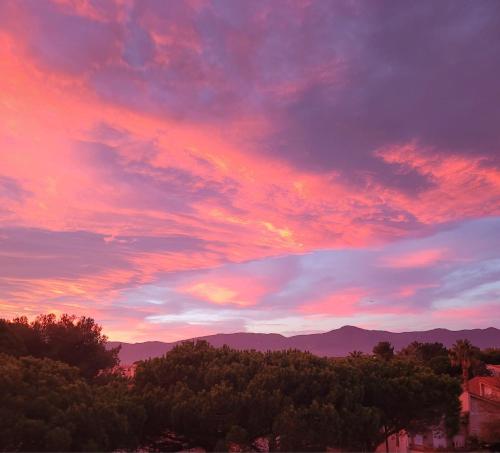 un coucher de soleil avec des arbres et des montagnes en arrière-plan dans l'établissement La goélette, à Saint-Cyprien