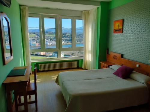 Dormitorio verde con cama, escritorio y ventana en Hotel Capellan, en Navia