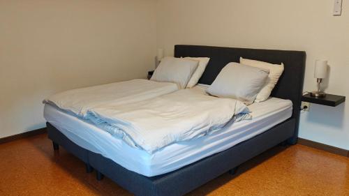 a bed with white sheets and pillows in a room at Brelaarheide in Aan de Wolfsberg
