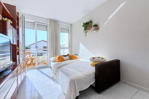 1 dormitorio con 1 cama, TV y balcón en Piso de dos habitaciones en playa de Ris- Noja, en Noja