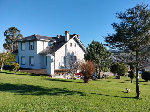 a white house with a tree in the grass at Hotel Capellan in Navia