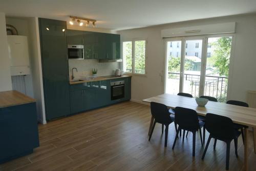 een keuken met groene kasten en een houten tafel en stoelen bij Disneyland Paris, appartement 70m², parking privé in Serris