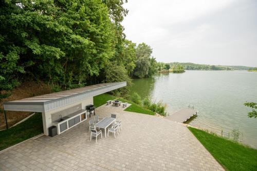 a patio with a table and chairs next to a lake at Gátőr Villa in Mőcsény