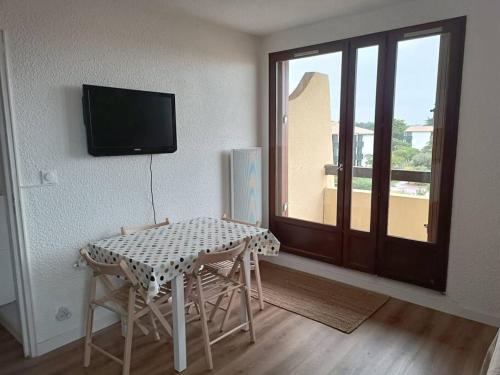 a room with a table and chairs and a television at Appartement T2, proche de la mer in Seignosse