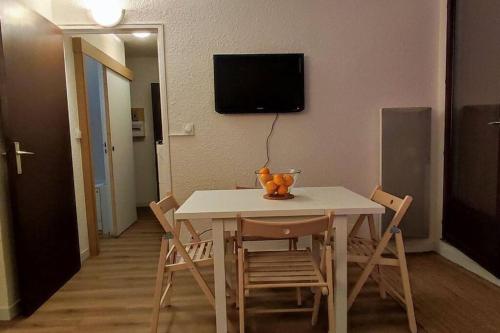 a dining room table with chairs and a television on the wall at Appartement T2, proche de la mer in Seignosse