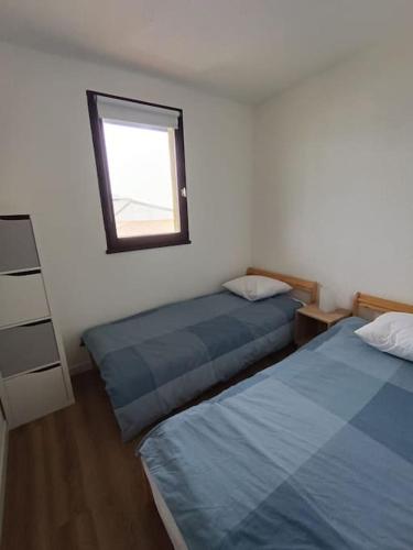 une chambre avec deux lits et une fenêtre dans l'établissement Appartement T2, proche de la mer, à Seignosse