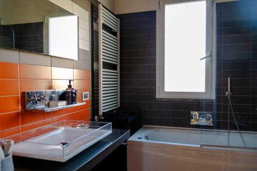 a bathroom with a sink and a tub and a window at Villa Marlene B&B in Albenga