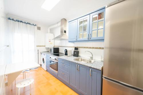 a kitchen with blue cabinets and a stainless steel refrigerator at Apartamentos GO - Único Sentido in Tordesillas