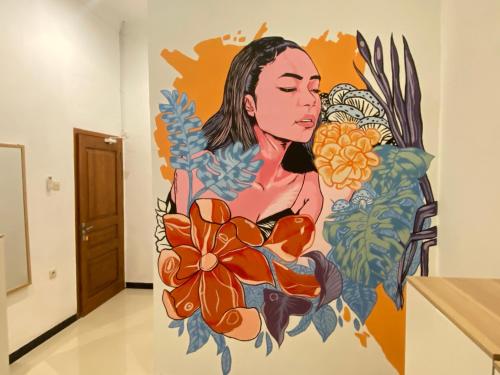 a mural of a woman with flowers on a wall at ReVive by Snooze in Banyuwangi