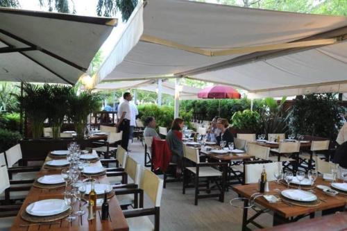 un restaurant avec des tables en bois et des parasols blancs dans l'établissement Cannes Palm Beach Parking, clim, wifi plage 2' à pieds, à Cannes