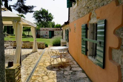 un patio avec une table et des chaises à côté d'un bâtiment dans l'établissement Cottage Casa Vinela, à Buje