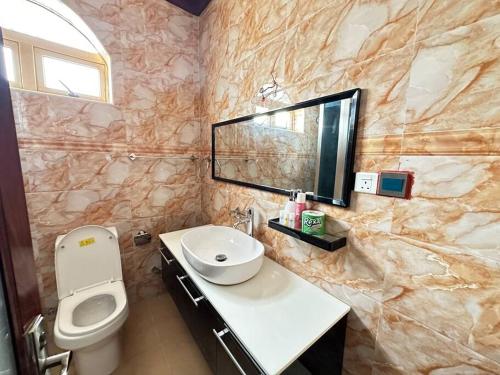 a bathroom with a sink and a toilet and a mirror at The O.C Luxury Rooms in Kiembi Samaki
