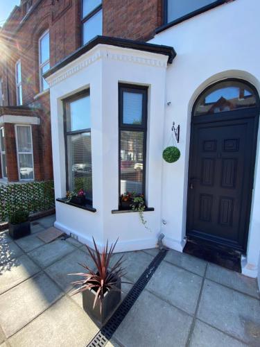 una puerta delantera de una casa blanca con una puerta negra en Loving Victorian Home For Your Belfast Escape!, en Belfast