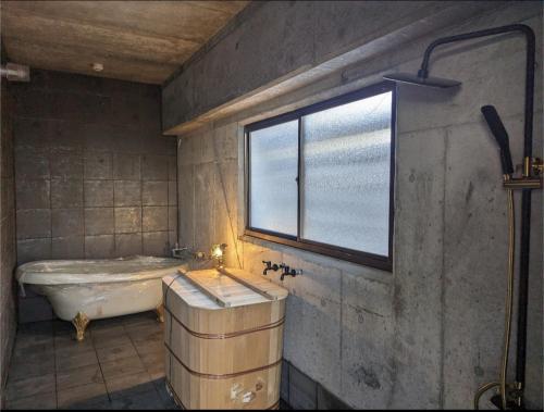 een badkamer met een bad, een wastafel en een raam bij 源泉かけ流し温泉＆プライベートサウナ付き一棟貸しVilla SOUQ Echigo-yuzawa Hanare in Yuzawa