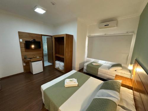 a hotel room with two beds and a television at La Torre Jaguarão in Jaguarão