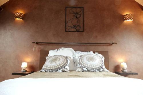 een slaapkamer met een bed met witte kussens en 2 verlichting bij Maison proche Disneyland Paris in Ozoir-la-Ferrière