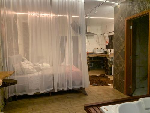 ein Zimmer mit einem weißen Vorhang in einer Küche in der Unterkunft Chalé Romântico Campina Grande do sul in Campina Grande do Sul