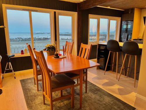 a dining room with a table and chairs and windows at House by the ocean with midnight sun view in Eggum