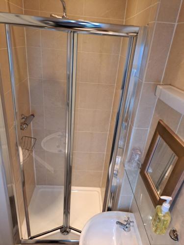 a shower with a glass door next to a sink at Pilkingtons Guest House Accrington in Accrington