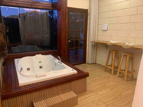 een groot bad in een kamer met een raam bij Chalé Romântico C. grande do Sul in Campina Grande do Sul