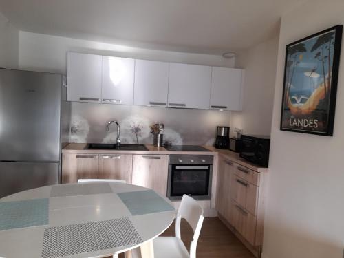 une cuisine avec des armoires blanches et une table avec des chaises dans l'établissement Léon, à Dax