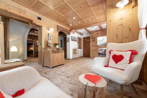 a living room with a white chair and a red heart pillow at Villa Adria B&B in Canazei