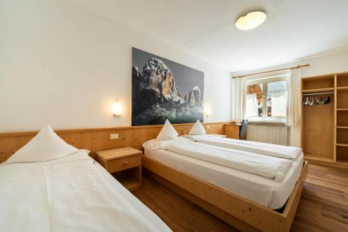 a bedroom with two beds and a painting on the wall at Villa Adria B&B in Canazei