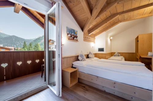 a bedroom with a bed and a balcony at Villa Adria B&B in Canazei
