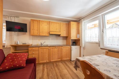a kitchen with wooden cabinets and a table in a room at Villa Adria B&B in Canazei