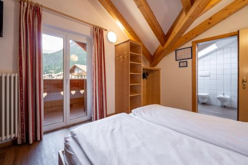 a bedroom with a bed and a large window at Villa Adria B&B in Canazei