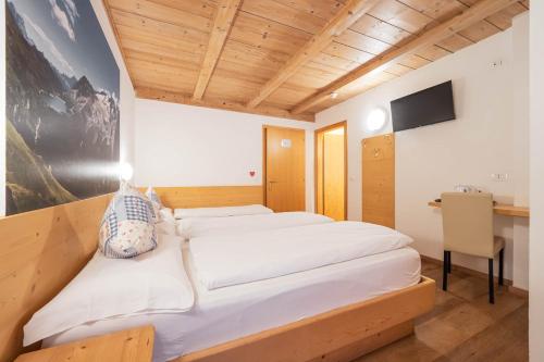 a bedroom with a large bed with white sheets at Villa Adria B&B in Canazei